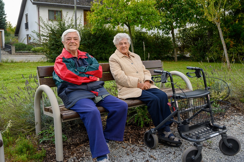 Zwei Bewohnerinnen sitzen im Garten auf einer Bank
