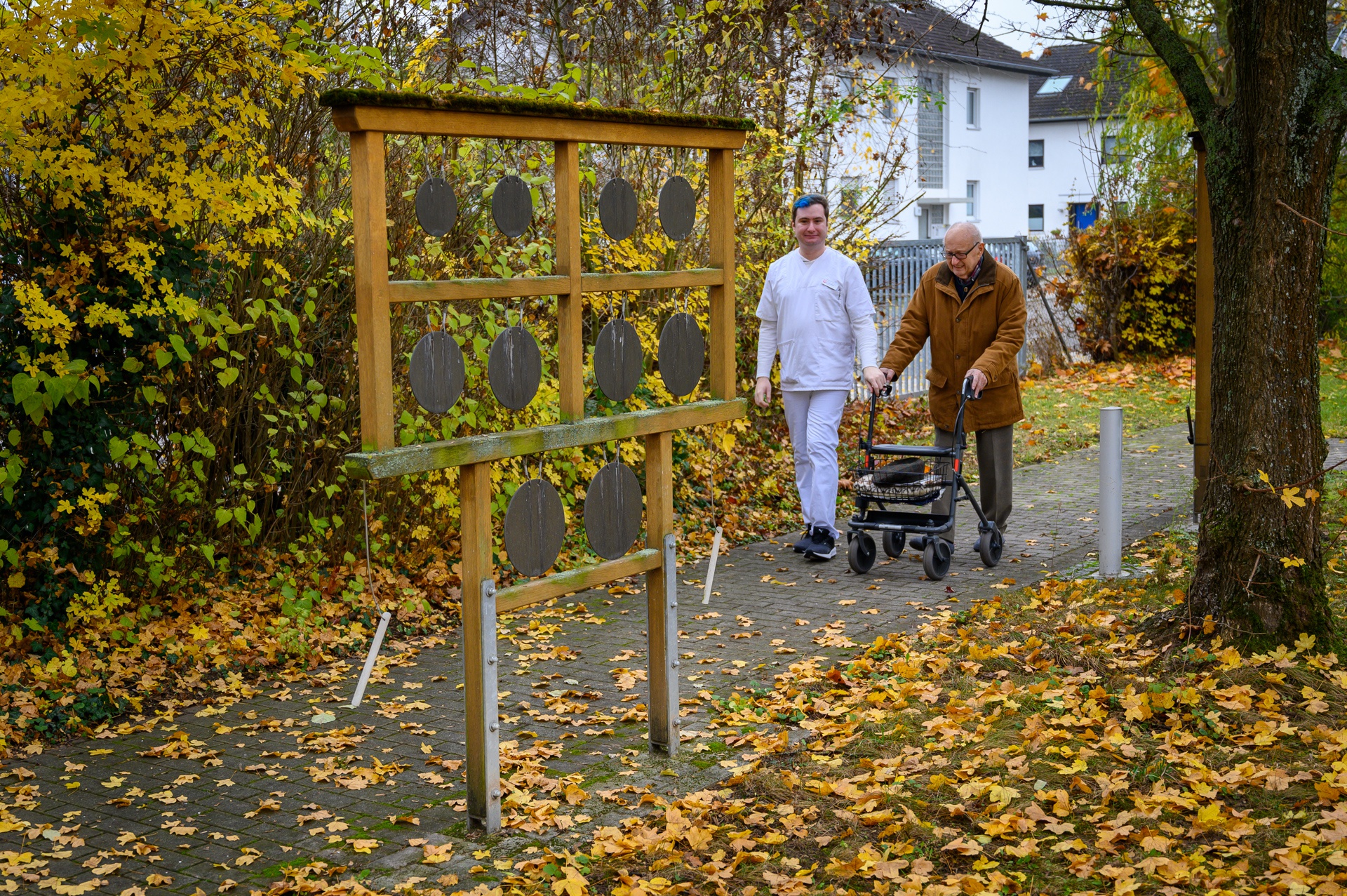 Eine Pfleger und ein Bewohner machen einen Spaziergang im Garten bei den Klanggeräten